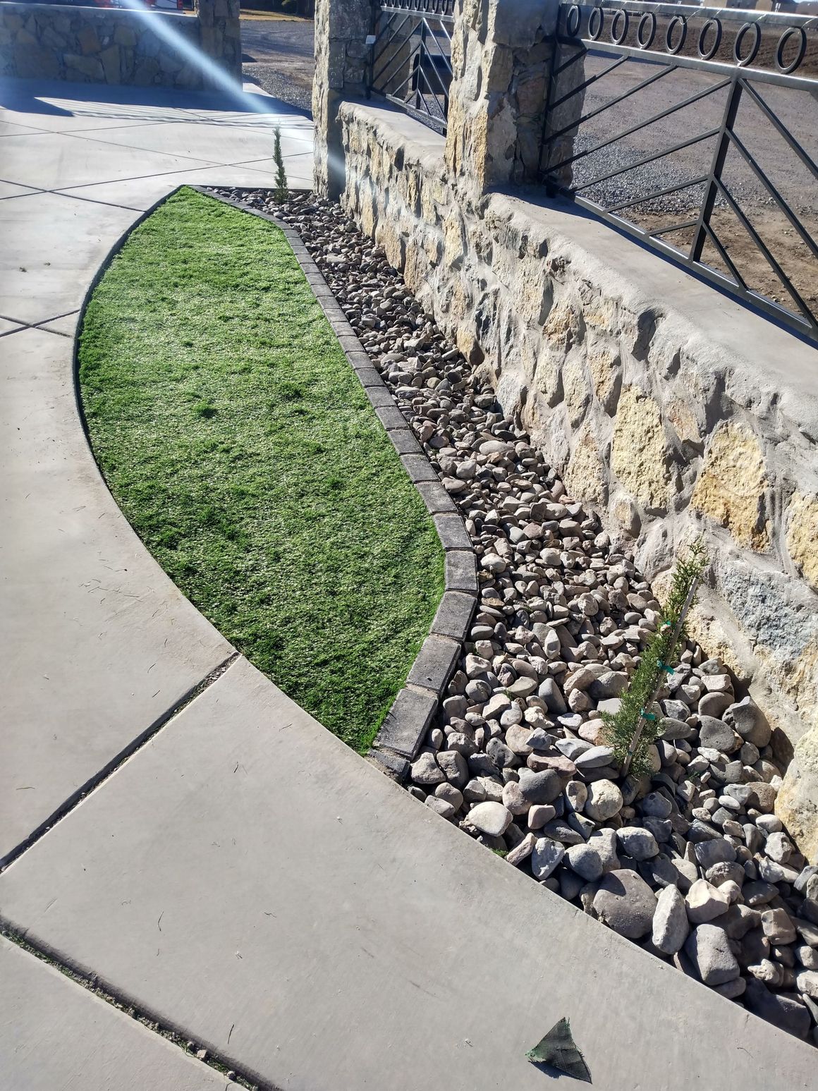 A concrete walkway with grass and rocks on the side of it