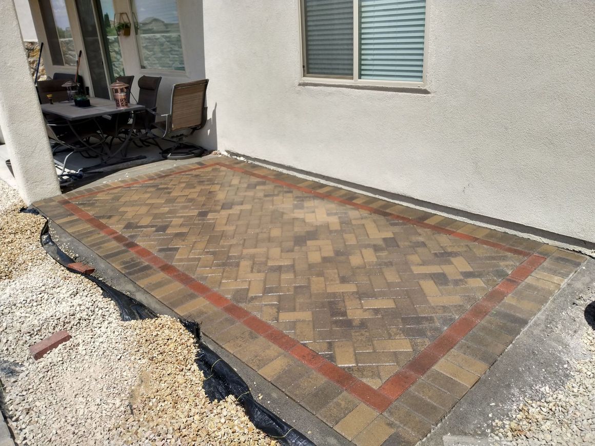 A brick patio is being built in front of a house.