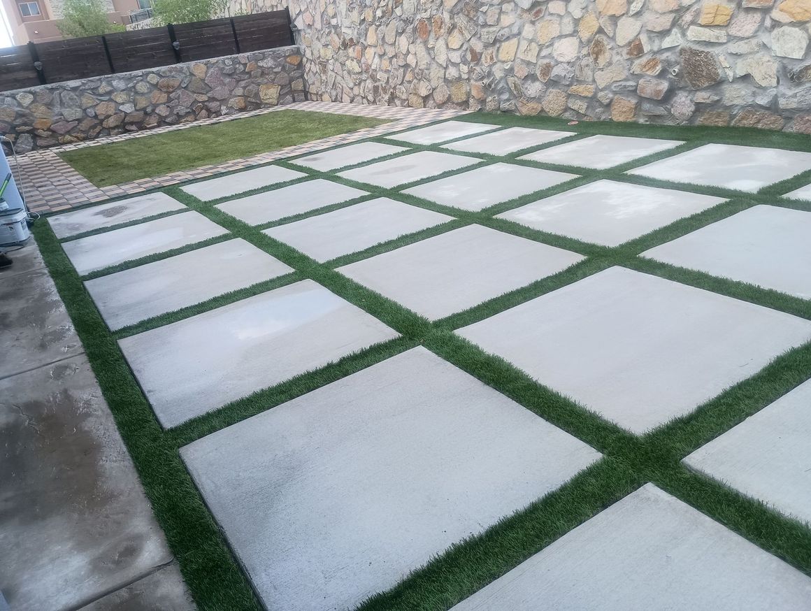 A patio with a lot of square tiles and grass.