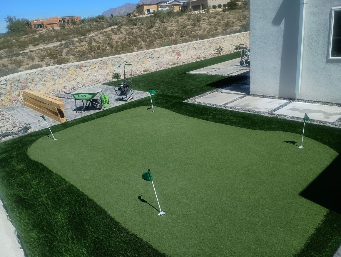 A putting green in a backyard with a house in the background