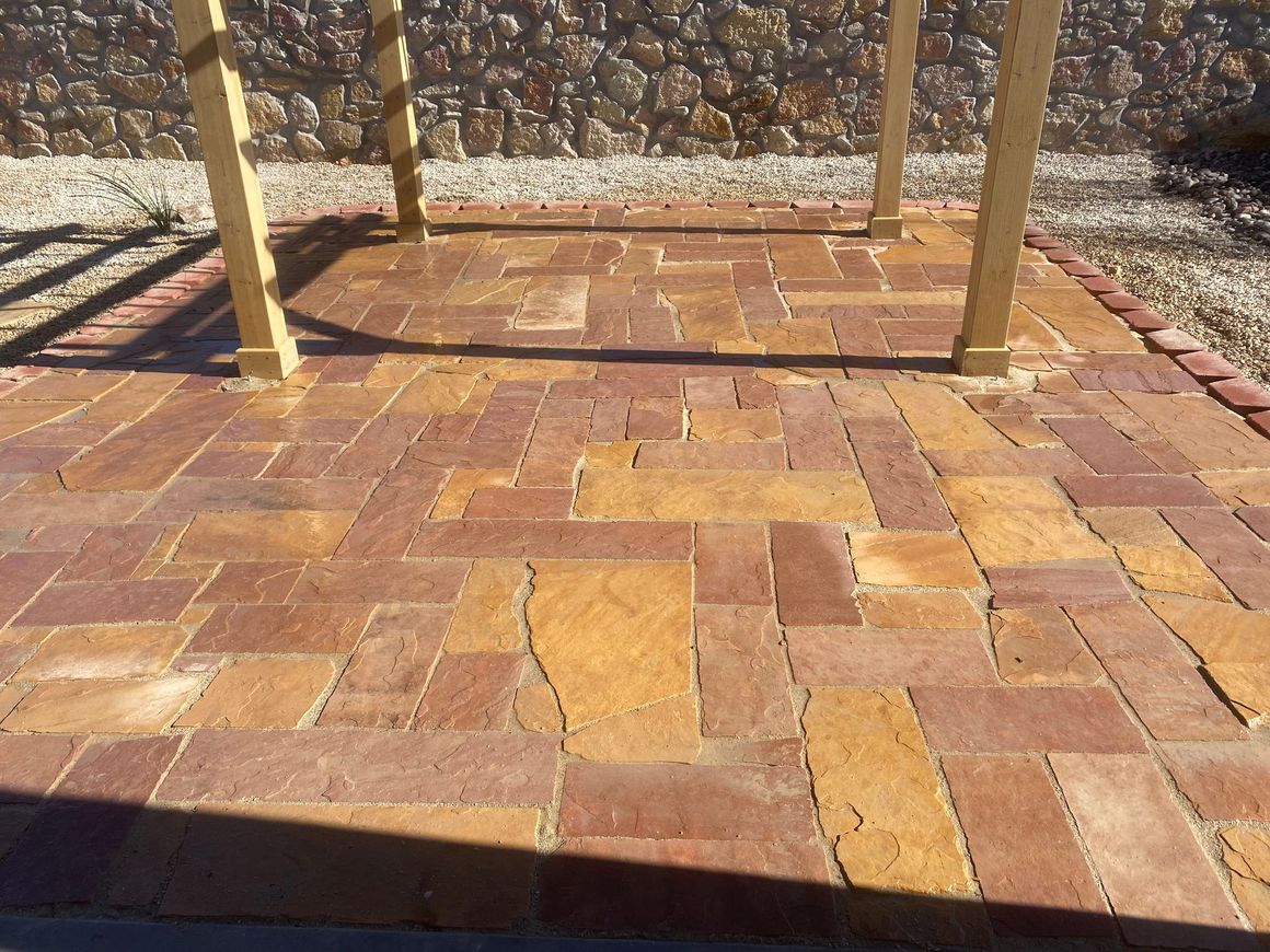 A brick patio with a wooden pergola in the background