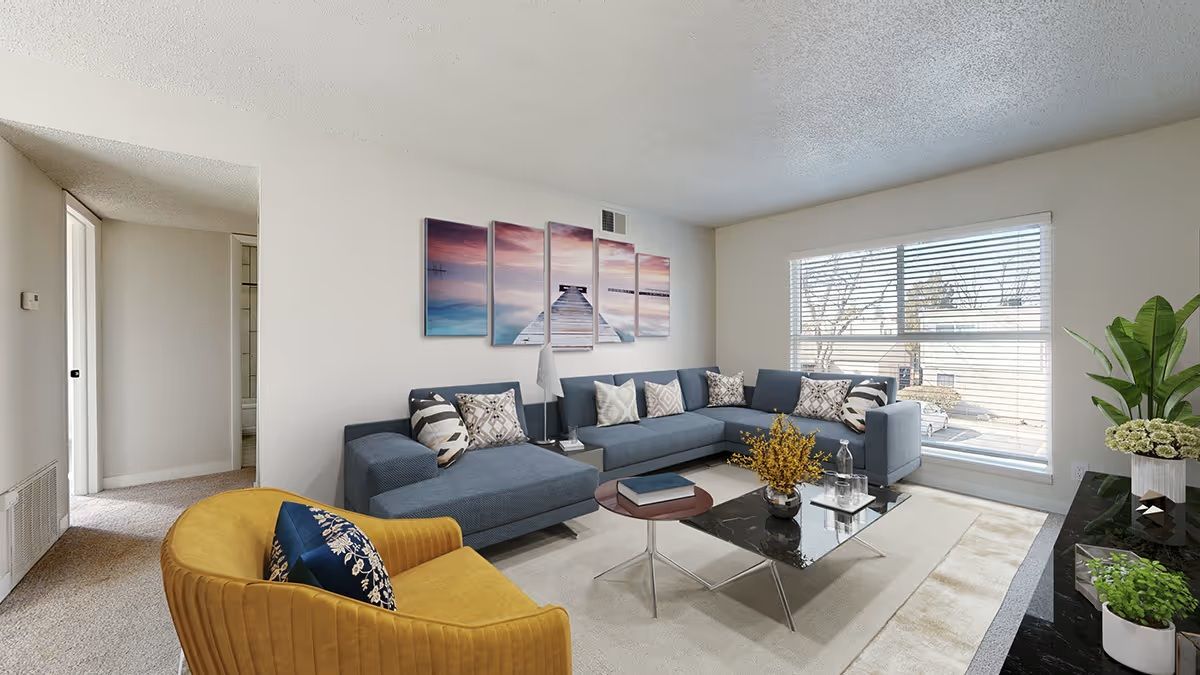A living room featuring a blue sectional sofa, a yellow armchair, a coffee table, and beach-themed wall art.