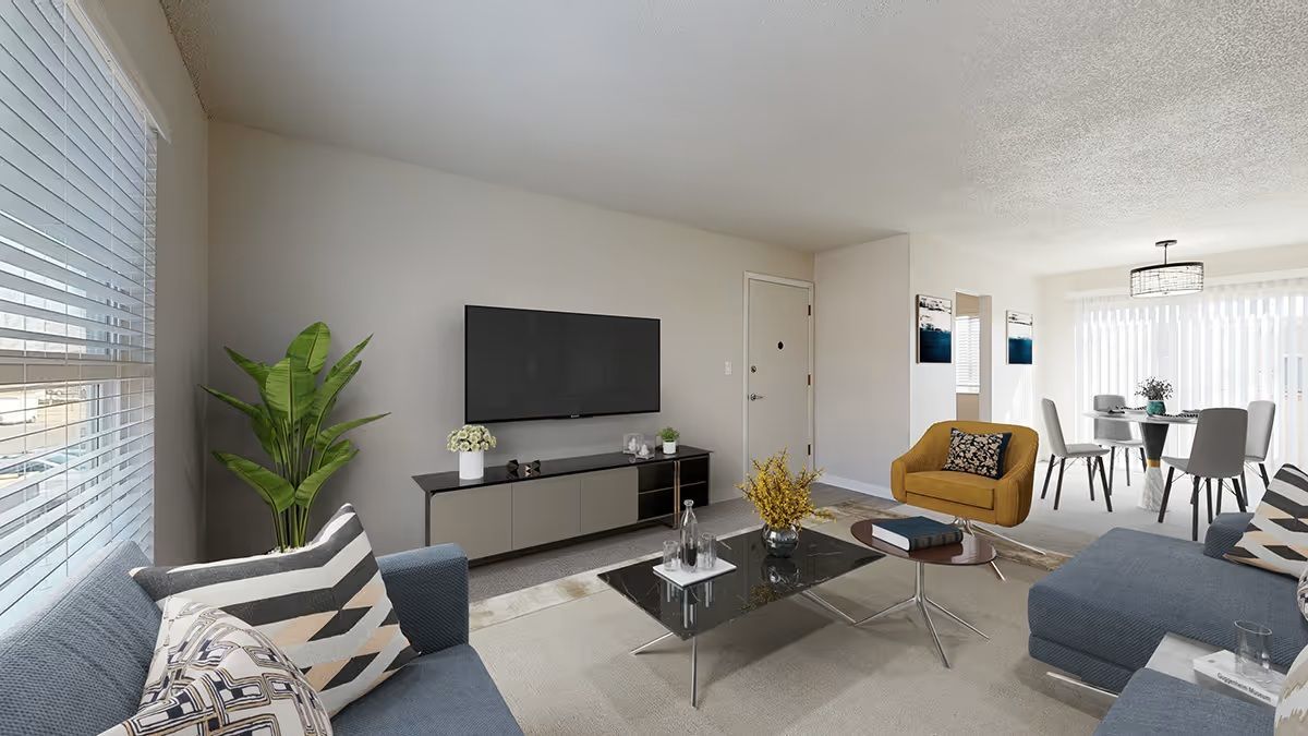 A modern, neutrally-toned living room featuring a TV, gray sofa, coffee table, yellow accent chair, and dining area.