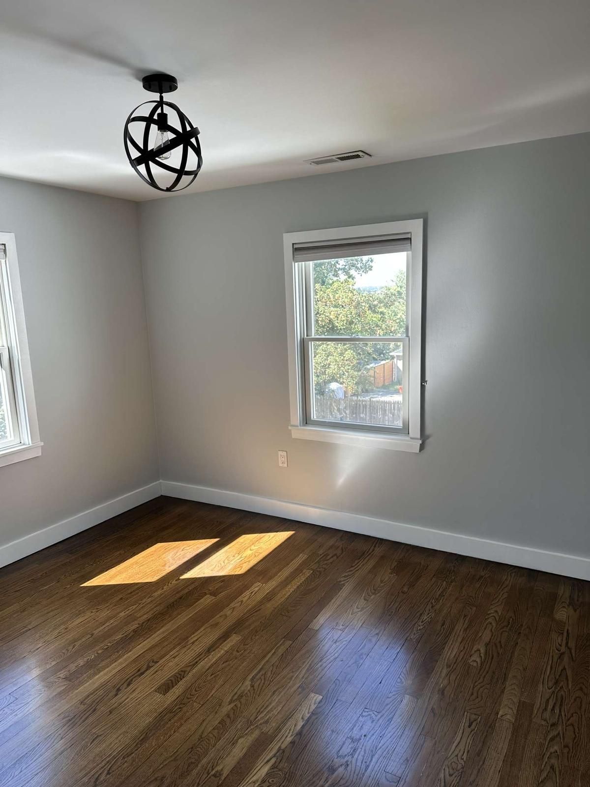 An empty room with hardwood floors and a window.