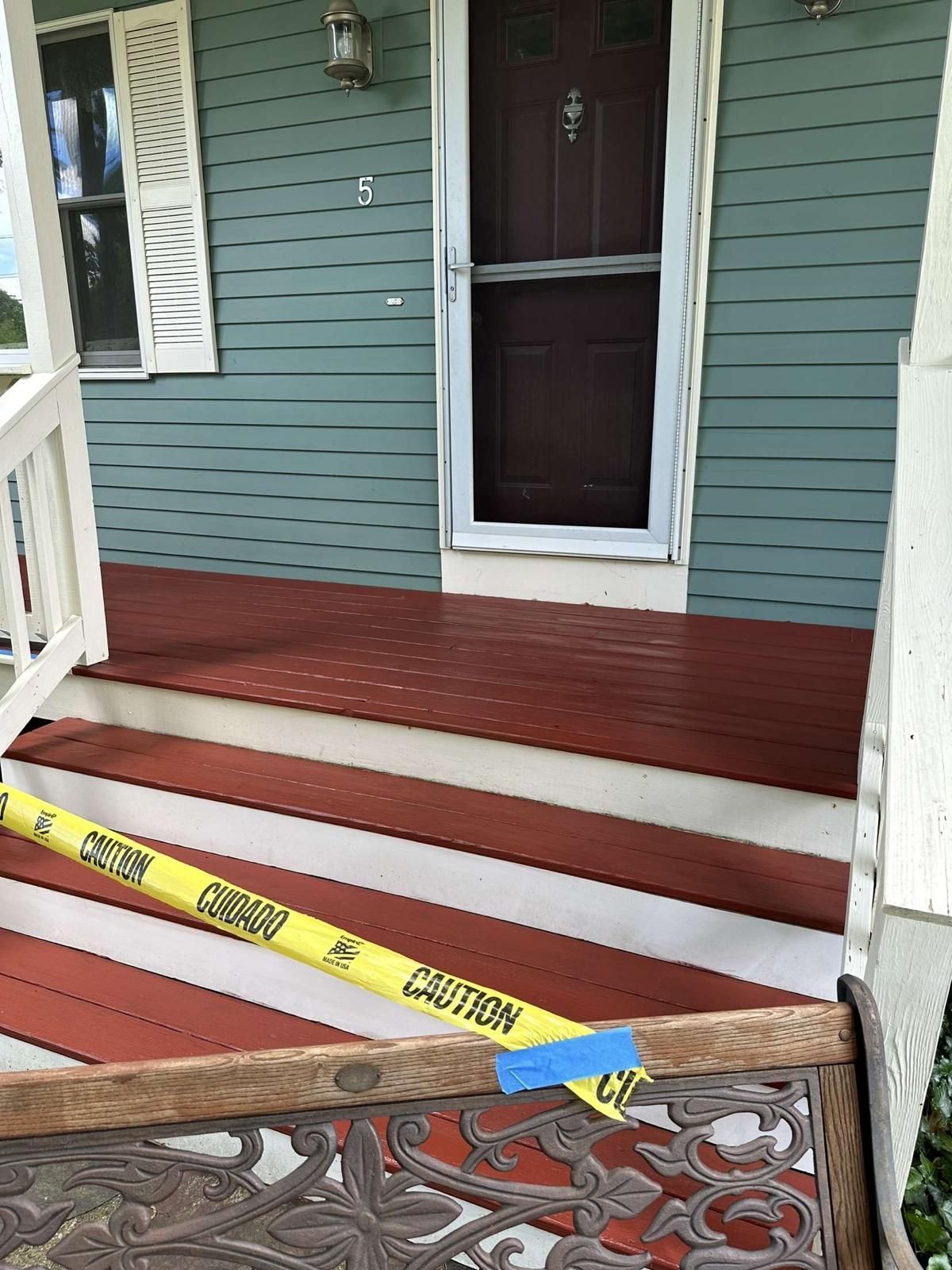 A yellow caution tape is sitting on the porch of a house.