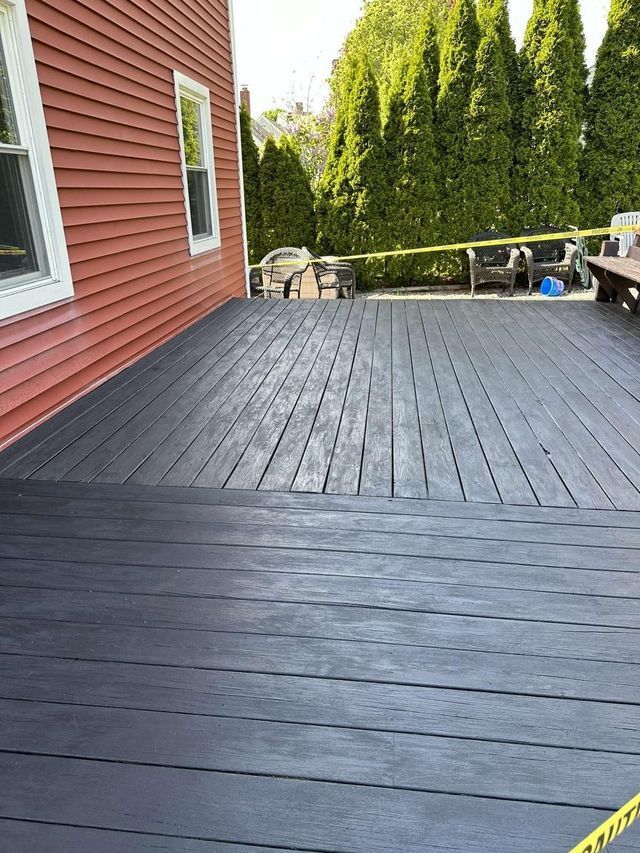 A black deck is sitting in front of a red house.