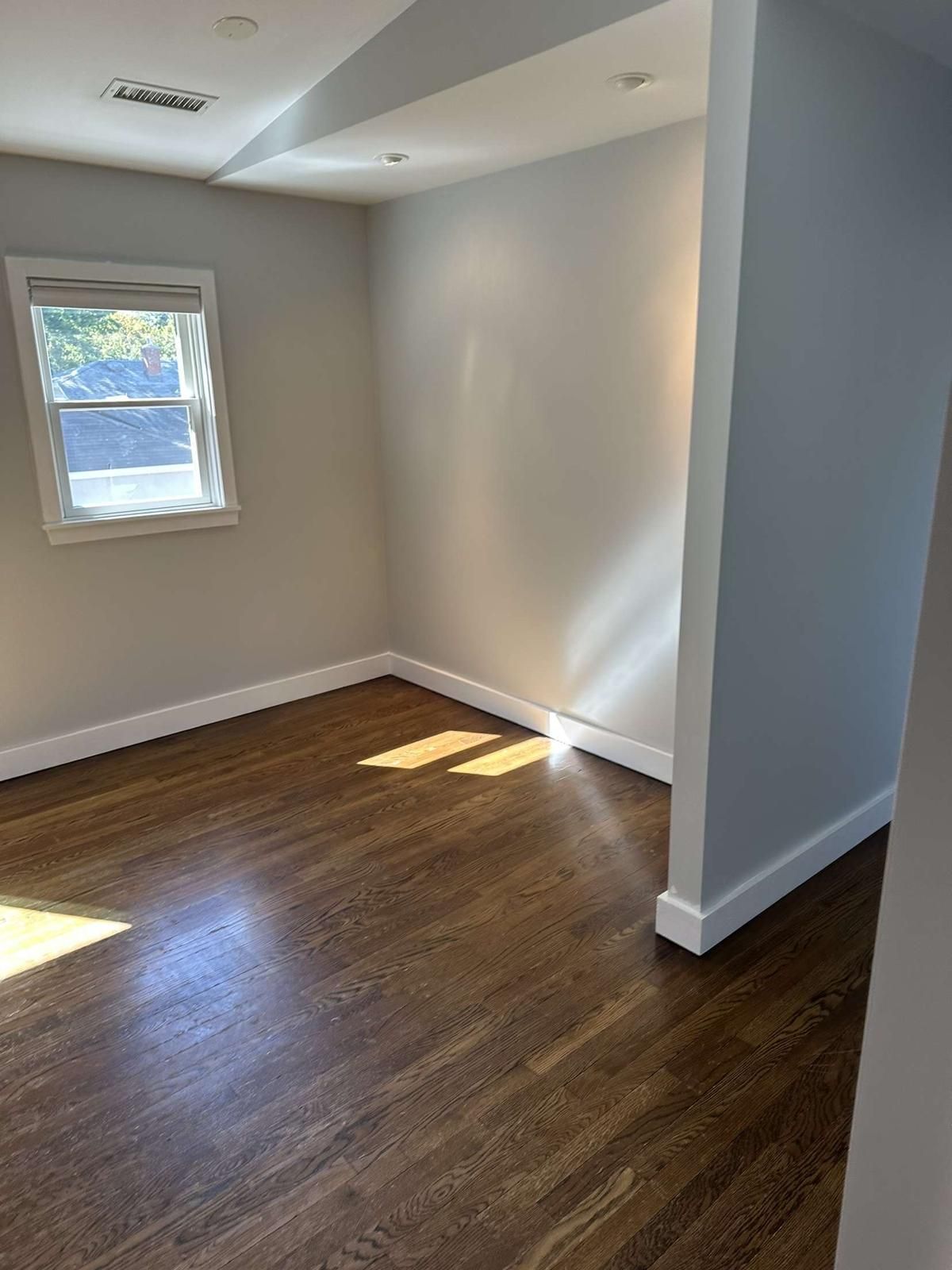 An empty room with hardwood floors and a window.
