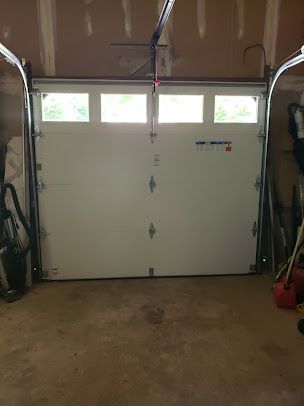 A white garage door is open in a garage.