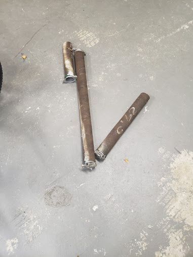 Two pieces of metal are laying on a concrete floor.