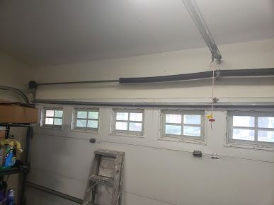 A garage with a garage door open and a ladder.