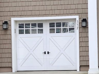 A white garage door is on the side of a house.