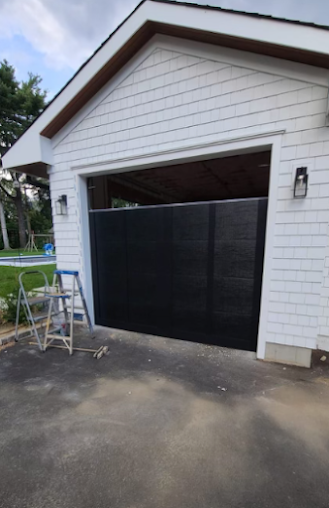 A white garage with a black door is being painted.