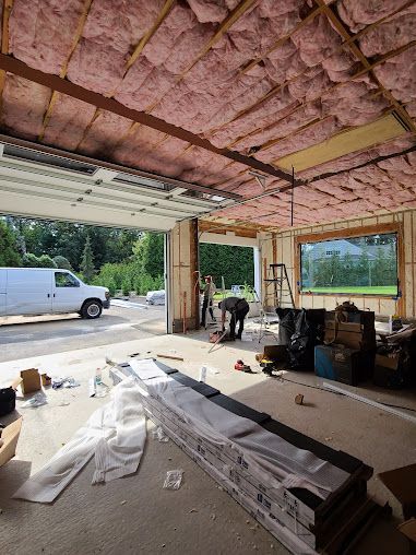 A man is working in a garage with insulation on the ceiling.