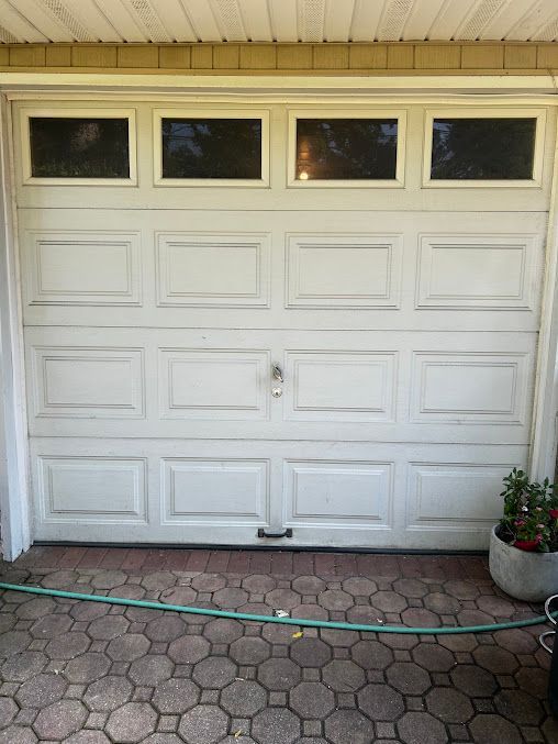 A white garage door with a green hose attached to it.