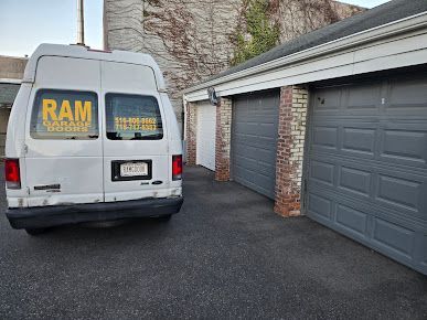 A white van is parked in front of two garage doors.