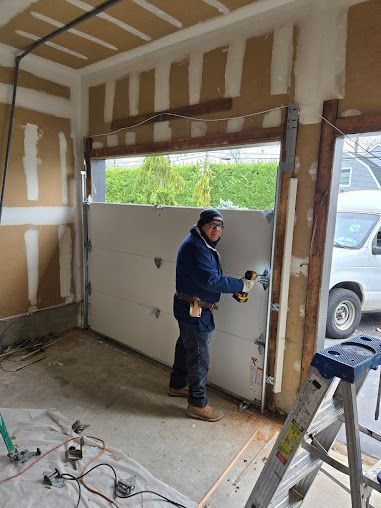 A man is working on a garage door in a garage.