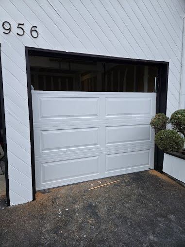 A white garage door is open on a white house.