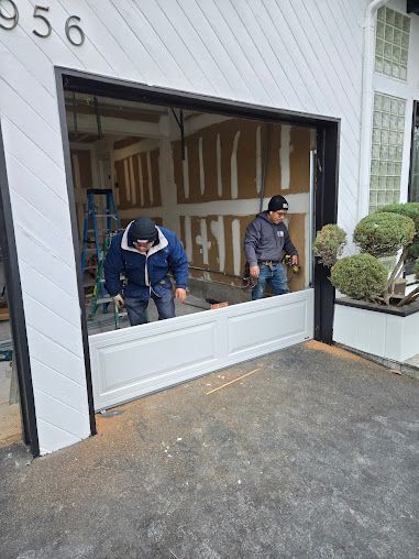 Two men are working on a garage door.