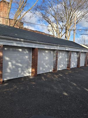 A row of garage doors are lined up next to each other on a brick building.