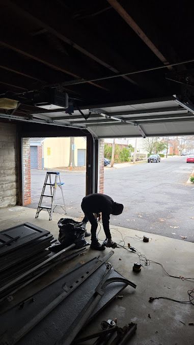 A man is working on a garage door in a garage.