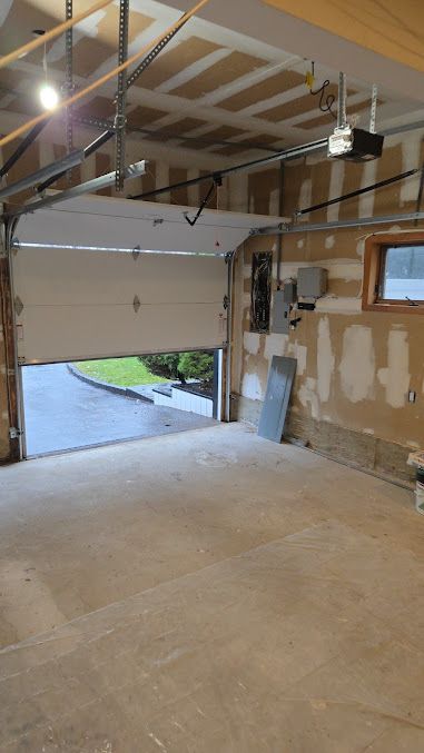 An empty garage with a garage door open and a window.