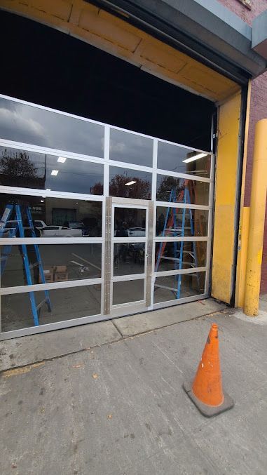 A large glass garage door is being installed on the side of a building.