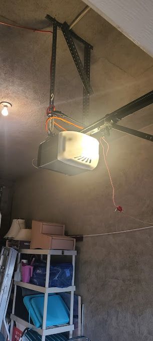 A garage door opener is hanging from the ceiling in a garage.