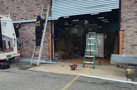 A man is standing on a ladder in front of a garage door.