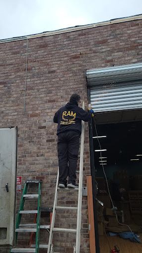 A man is standing on a ladder next to a garage door.