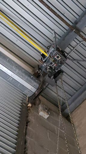 A chain is hanging from the ceiling of a garage door.