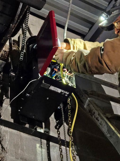A man in a brown jacket is working on a machine