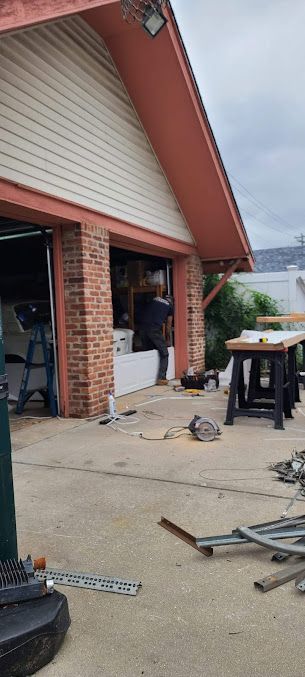 A man is working on the garage door of a house.