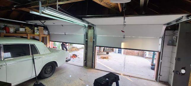 A white car is parked in a garage with the garage door open.