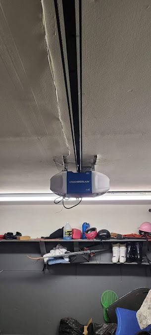 A garage door opener is hanging from the ceiling of a garage.