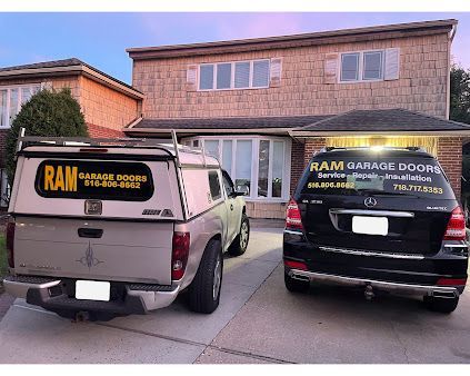 Two ram garage doors trucks are parked in front of a house.