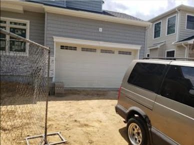 A van is parked in front of a house with a garage door.