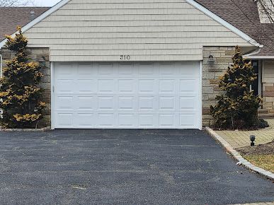A house with a white garage door and a black driveway.