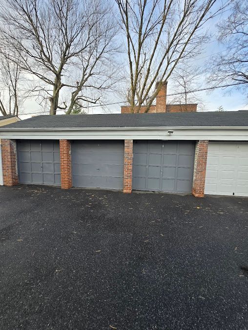 There are three garage doors on the side of a house.