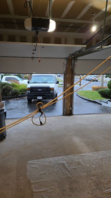 A white truck is parked in a garage with a rope hanging from the door.