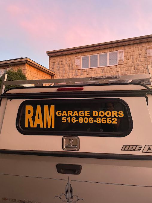 A white truck with a yellow sign on the back window that says `` ram garage doors ''.