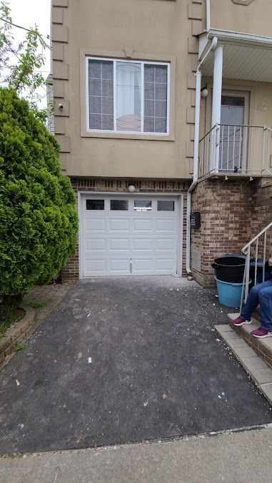 A man is standing in front of a house with a white garage door.