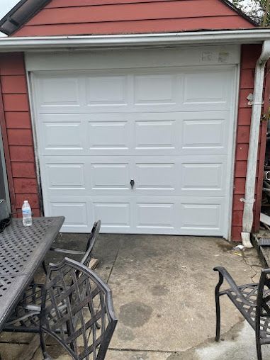 A white garage door is open next to a table and chairs.