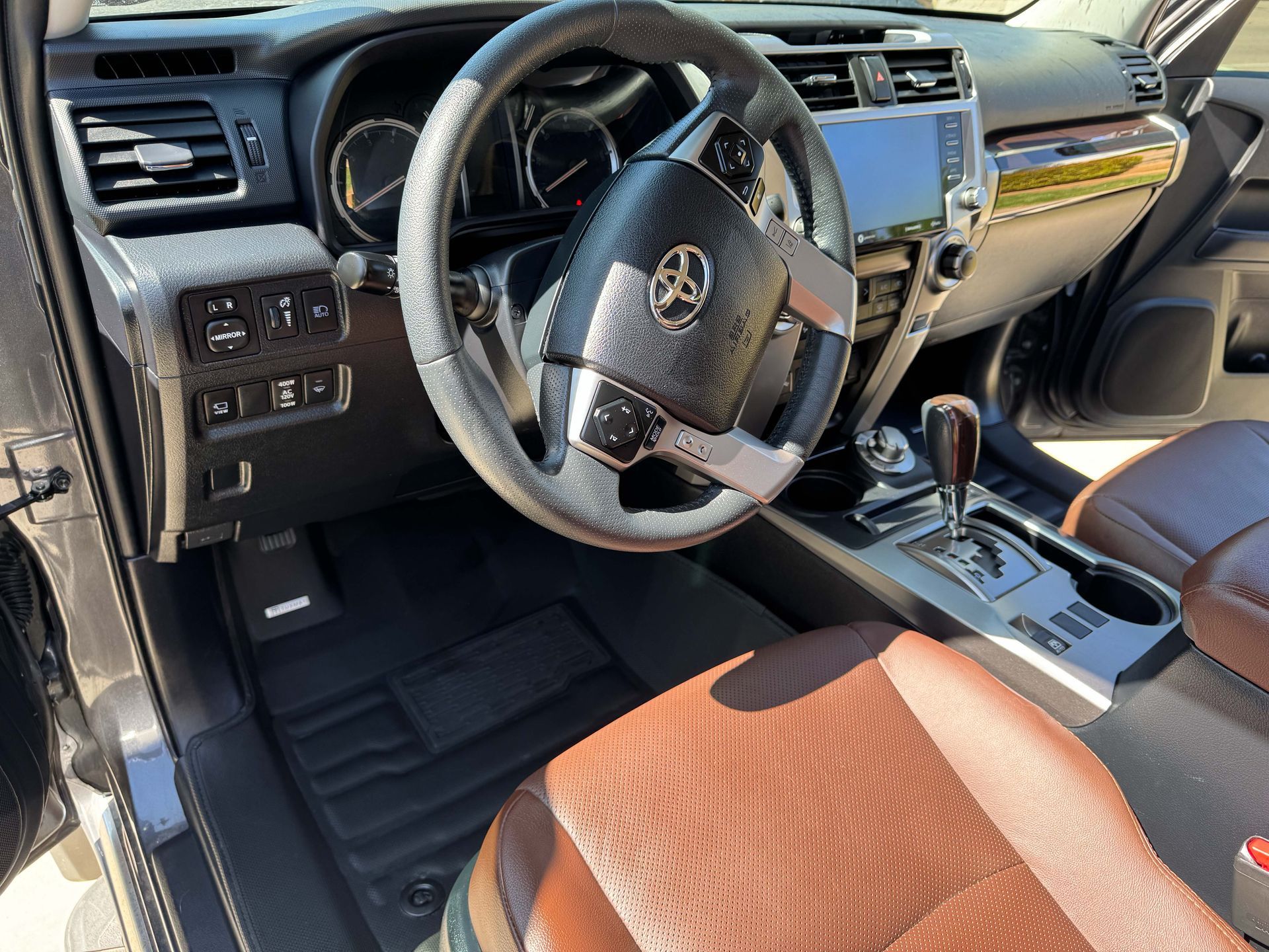 Interior of a Toyota 4Runner: brown leather seats, black dashboard, steering wheel, and infotainment screen.