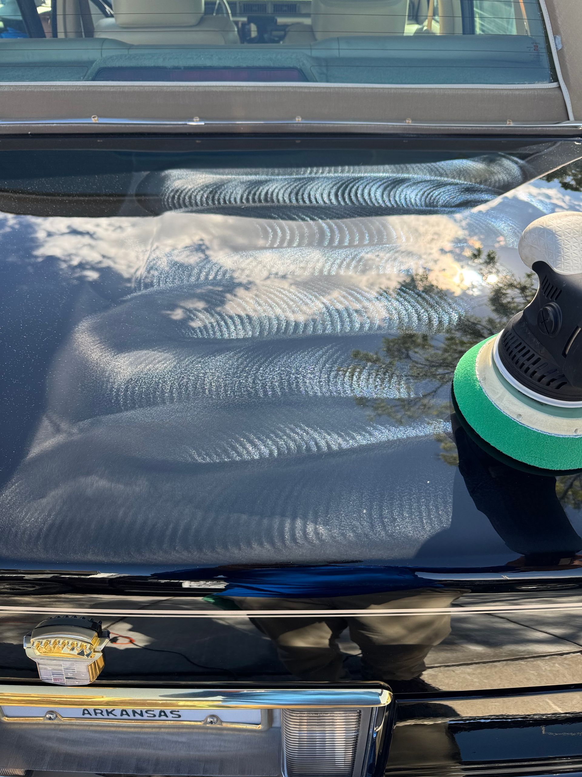 A white car roof being polished with a yellow and black power tool.