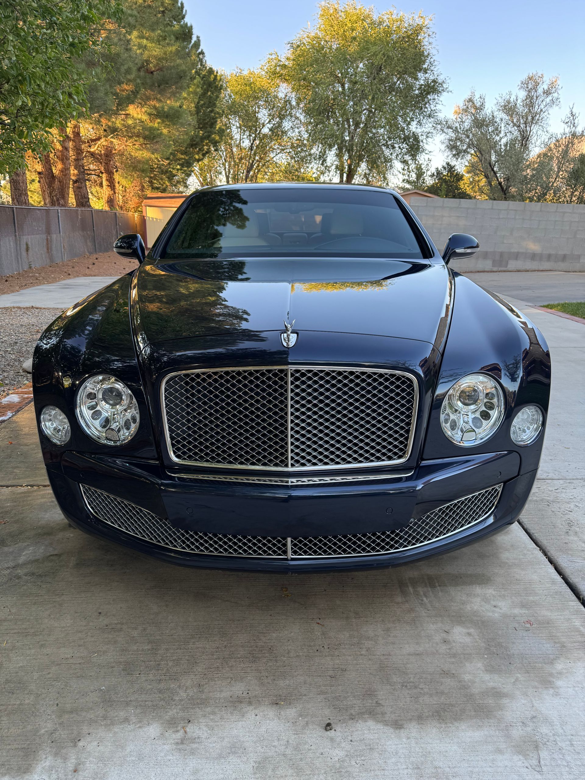 Black Bentley sedan parked on a driveway, facing the camera.