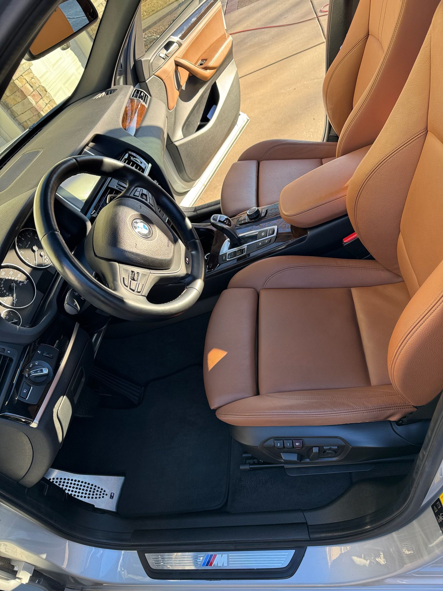 Interior car shot: brown leather seats, black steering wheel, silver trim.