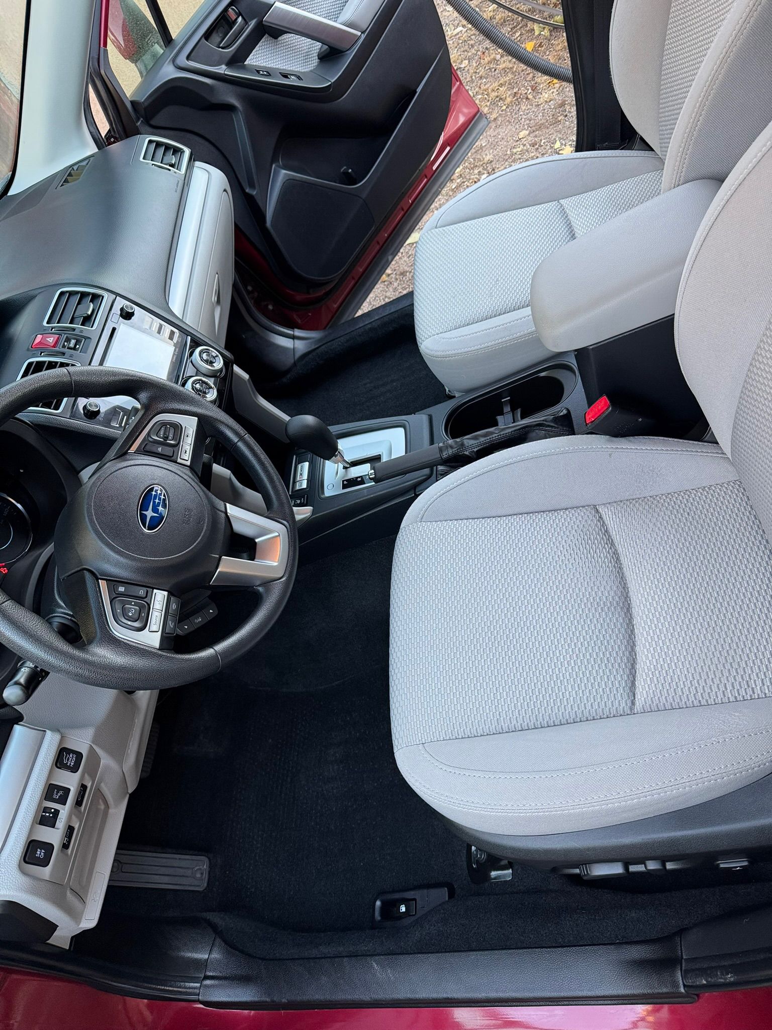 Interior view of a red car: seats, steering wheel, dashboard, and center console.