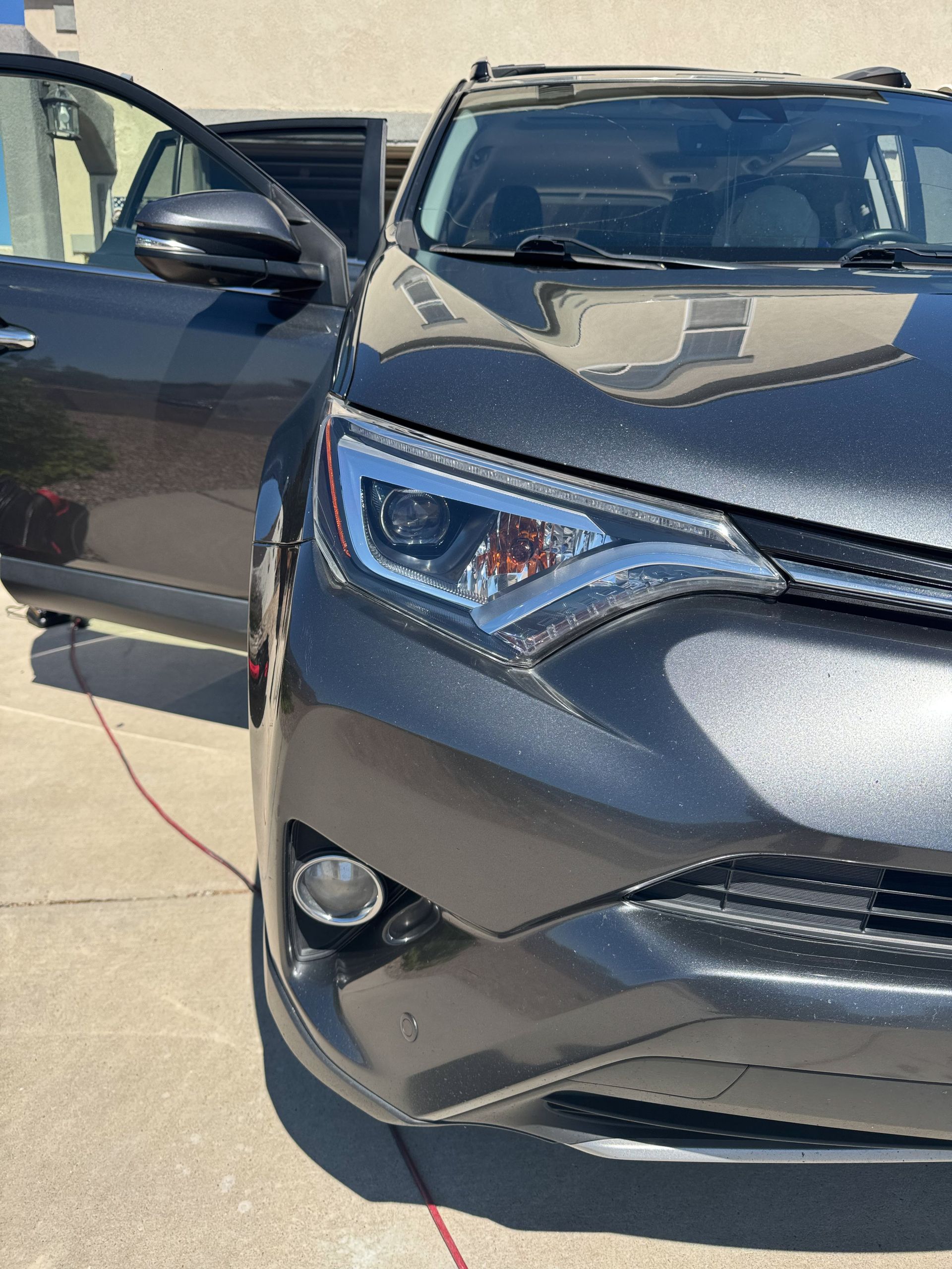 Gray SUV with driver's side door open, parked in front of a house.
