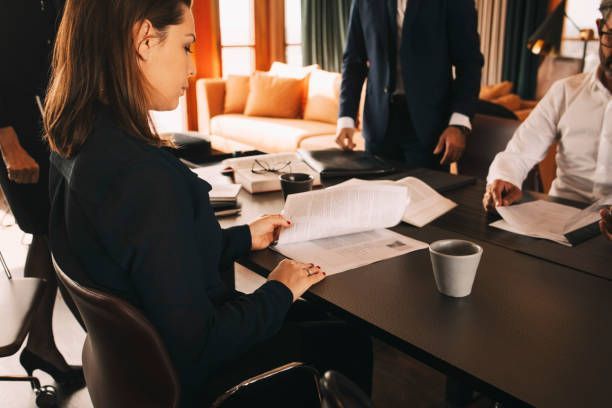 A woman is sitting at a table looking at papers.