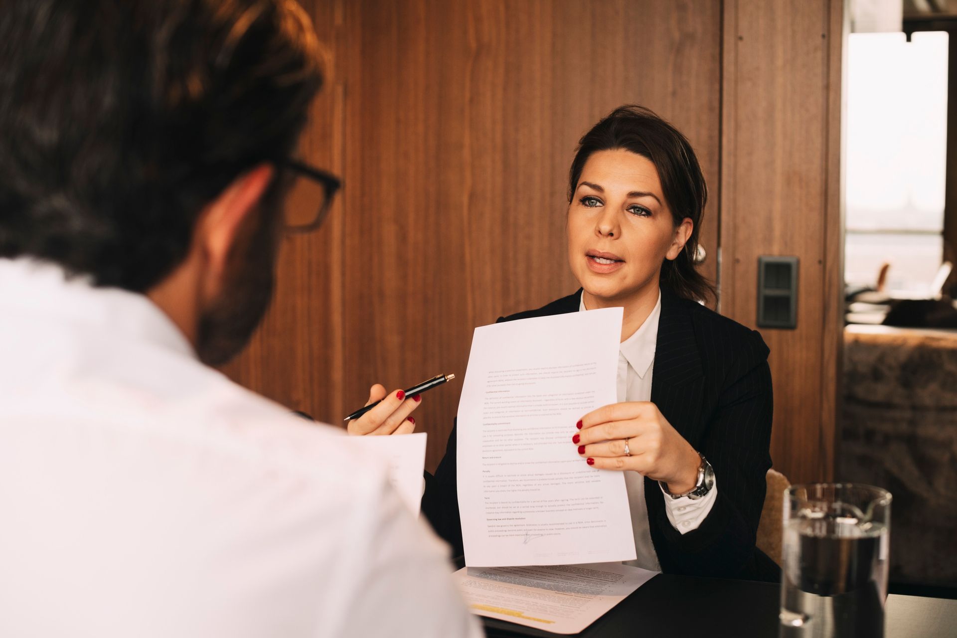 A woman is holding a piece of paper in front of a man during a job interview.
